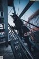 A woman in a black outfit is standing on a metal railing.